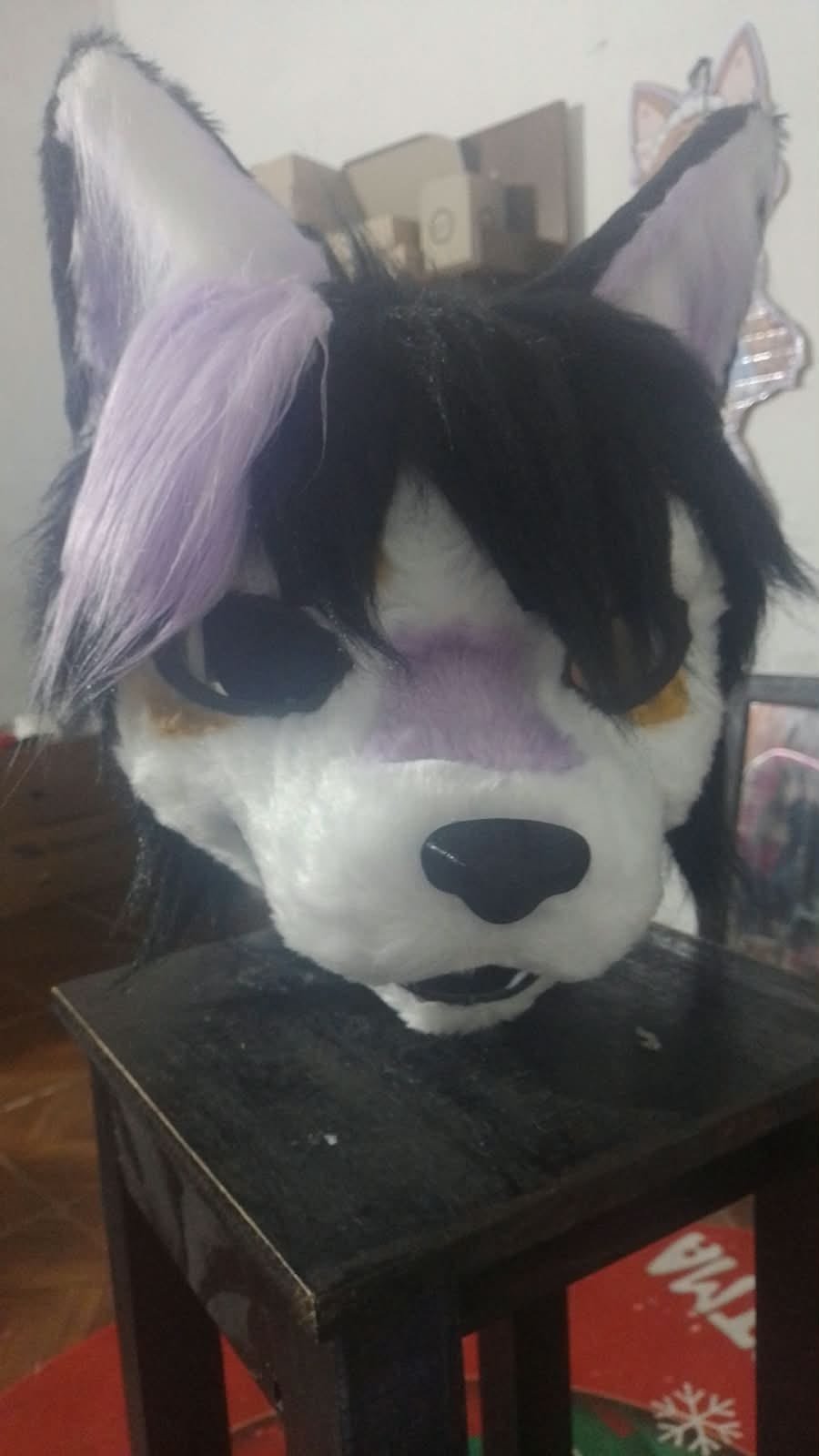 Cabeza de fursuit tipo lobo blanco y negro con nariz lila.